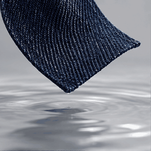 Concept animation of indigo denim dipping into clear water and lifting with droplets to illustrate washing.