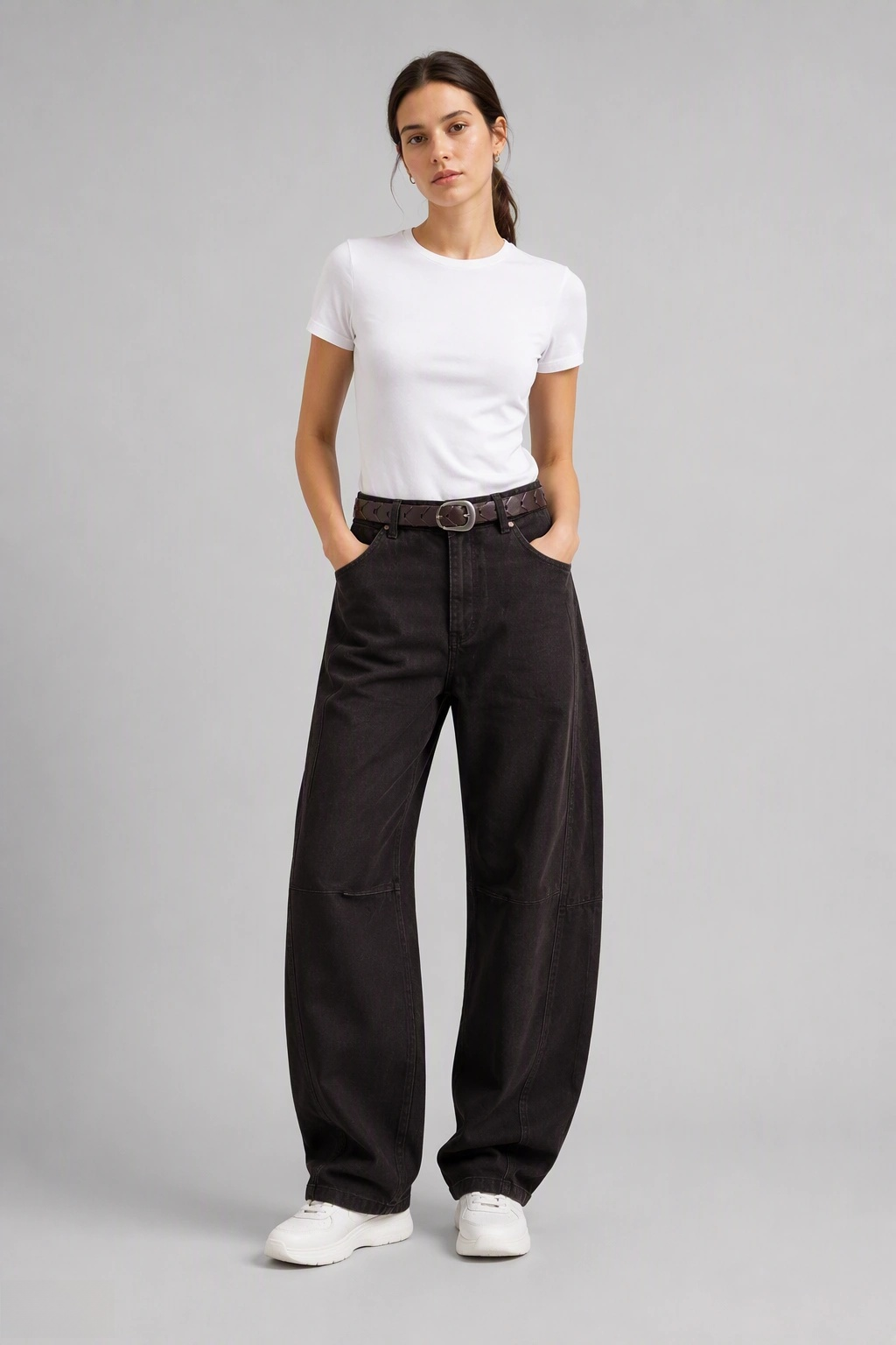 Full-body view of model wearing QAYQEY dark-brown curved-leg jeans with a white tee and white sneakers