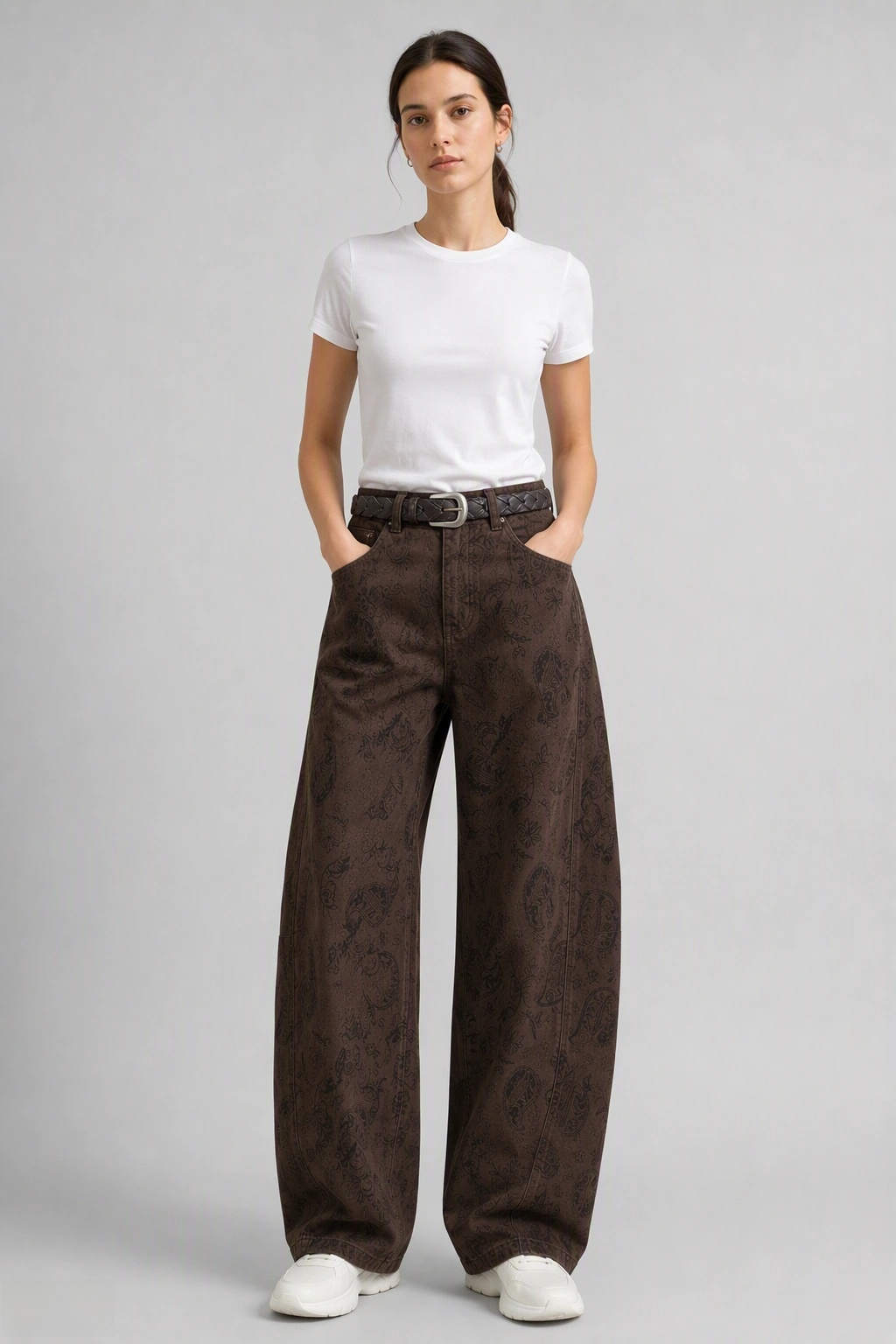 Full-body view of model wearing QAYQEY brown paisley-jacquard curved-leg jeans with a white tee and white sneakers
