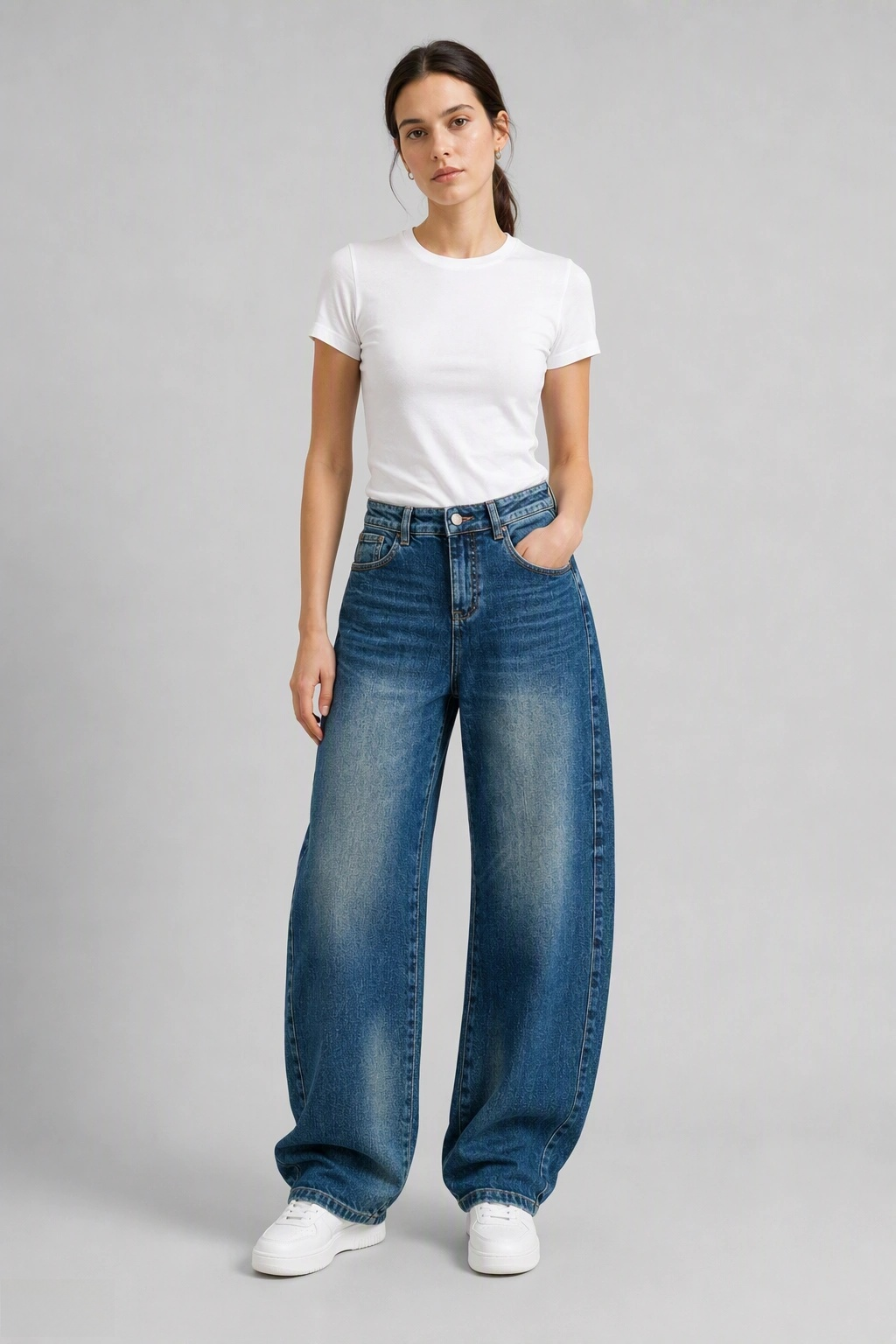 Full-body view of model wearing QAYQEY mid-blue flap-pocket curved-leg jeans with a white tee and white sneakers