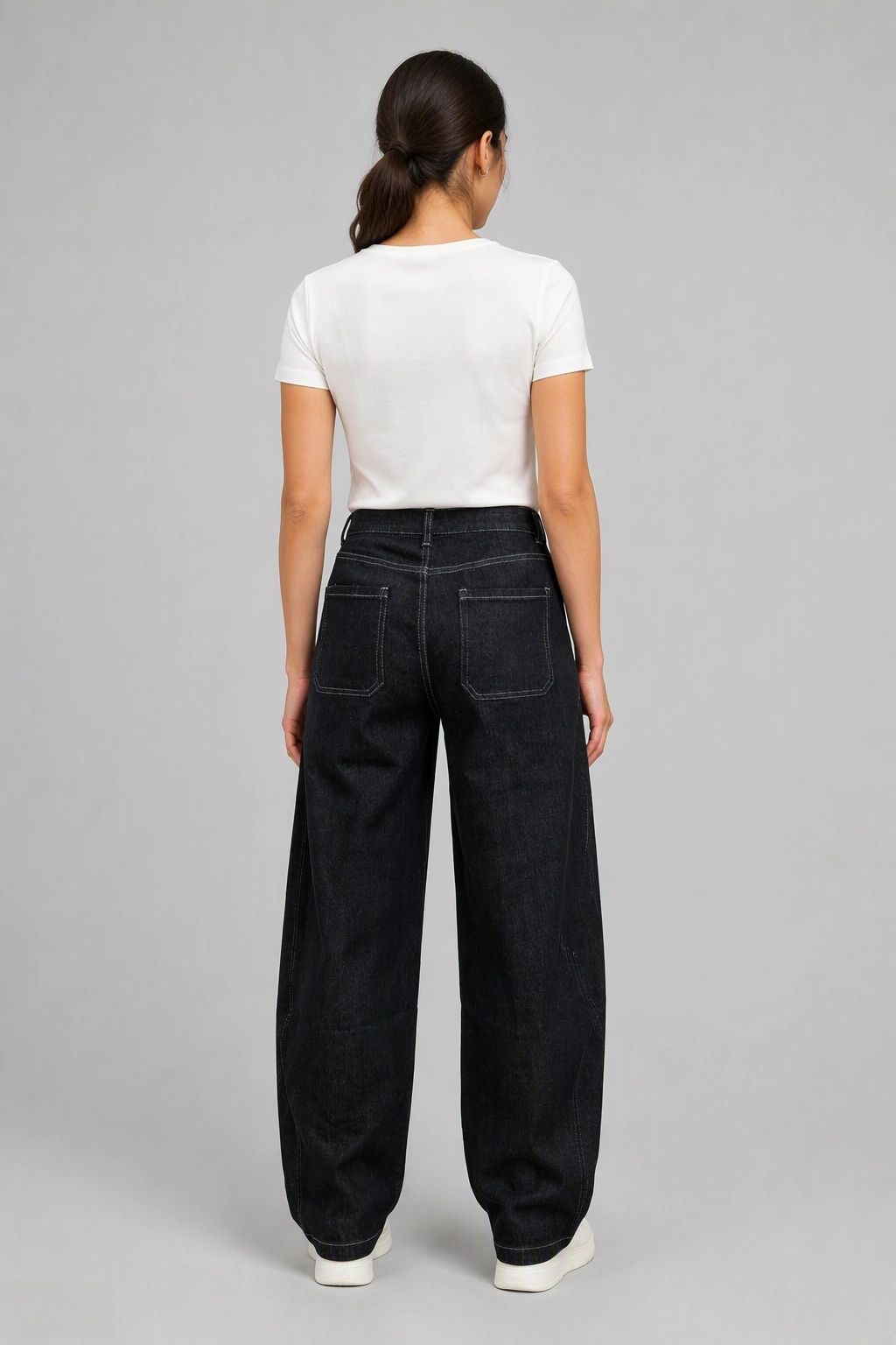 Back view of QAYQEY black-gray curved-leg jeans with contrast stitching, waist-down crop on model