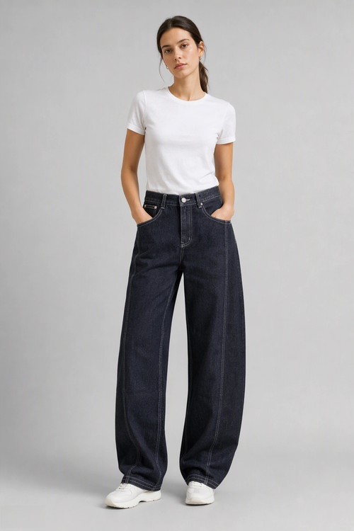Full-body view of model wearing QAYQEY black-gray curved-leg jeans with contrast stitching with a white tee and white sneakers
