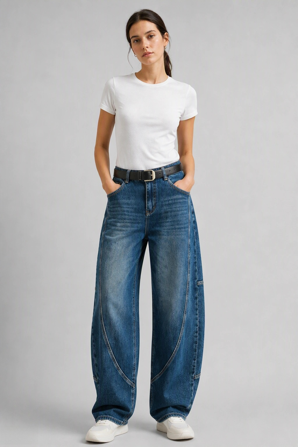 Full-body view of model wearing QAYQEY mid-blue washed curved-leg jeans with a white tee and white sneakers