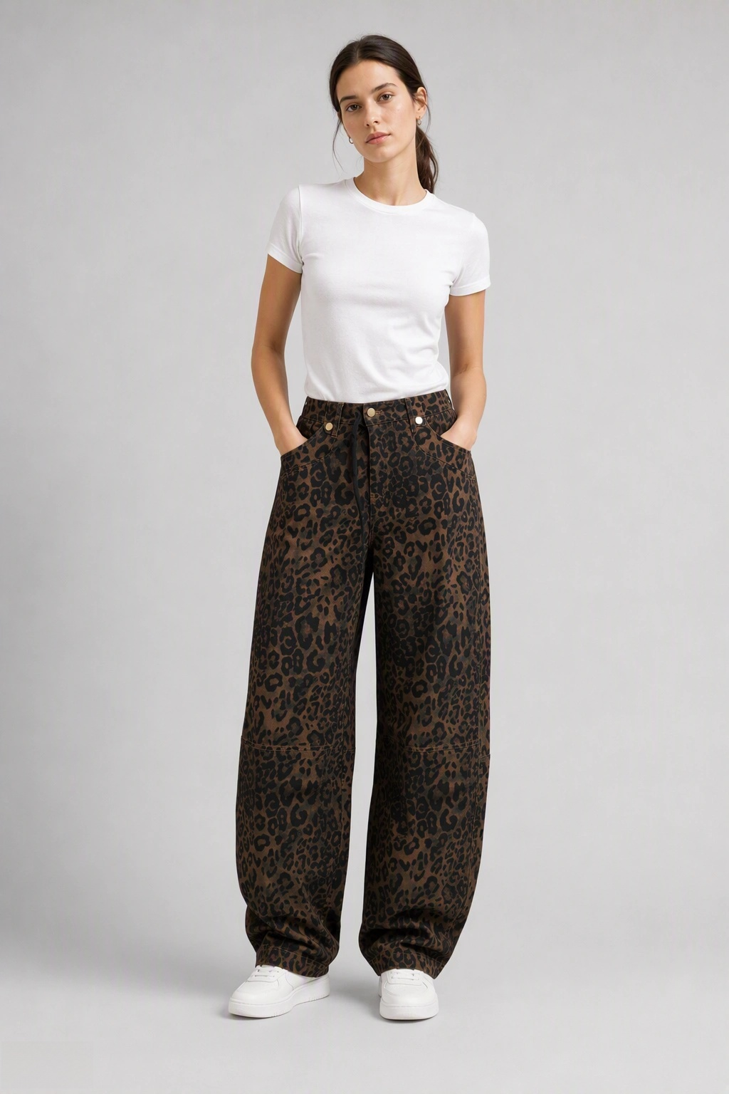 Full-body view of model wearing QAYQEY brown leopard-print curved-leg jeans with a white tee and white sneakers