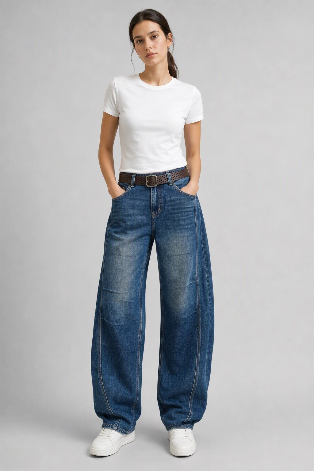 Full-body view of model wearing QAYQEY sun-faded mid-blue curved-leg jeans with a white tee and white sneakers