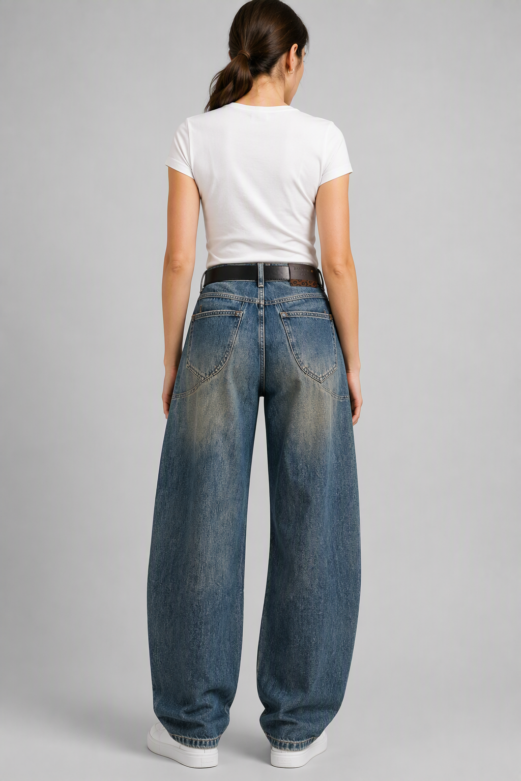 Back view of QAYQEY blue vintage-wash studded curved-leg jeans, waist-down crop on model