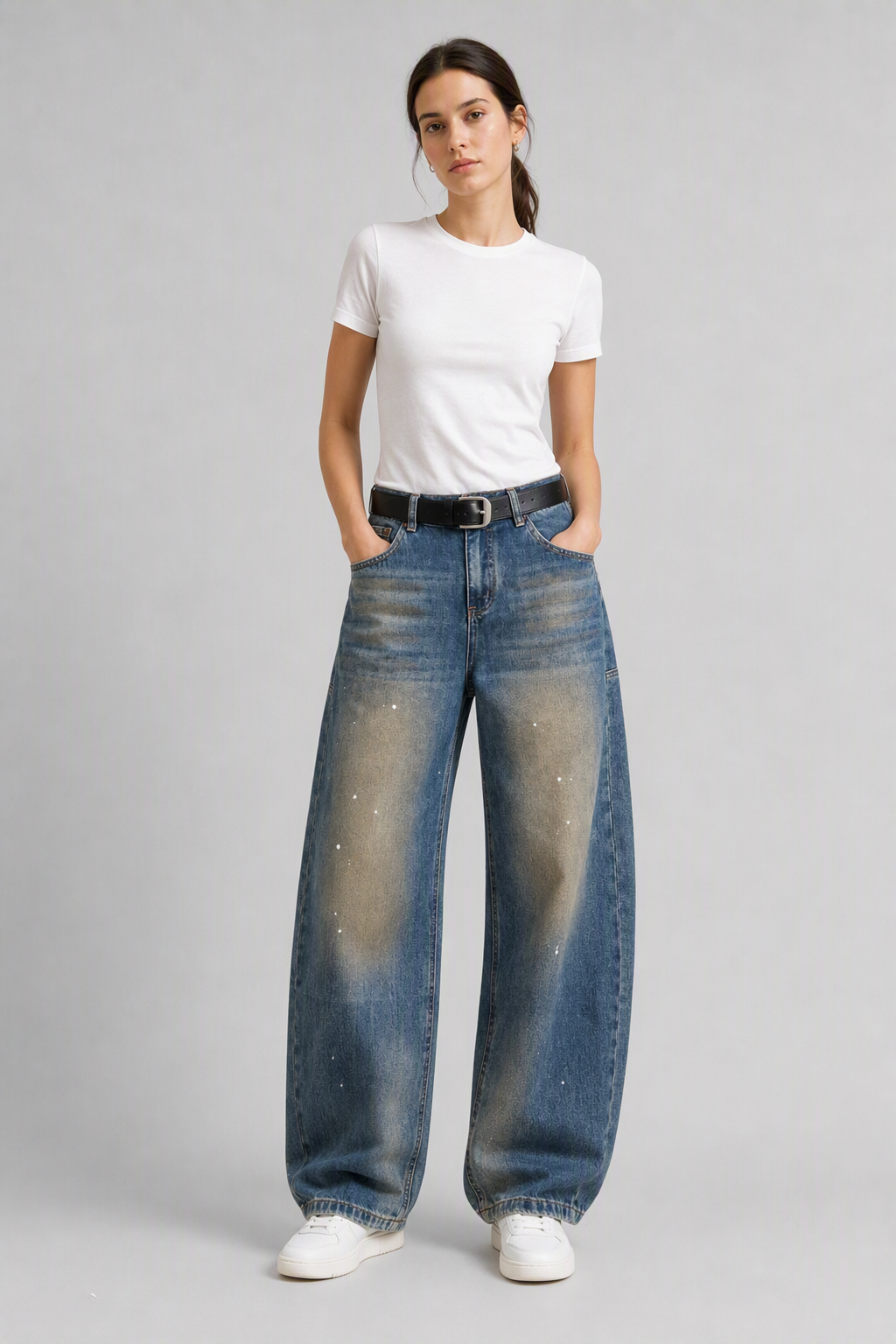 Full-body view of model wearing QAYQEY blue vintage-wash studded curved-leg jeans with a white tee and white sneakers