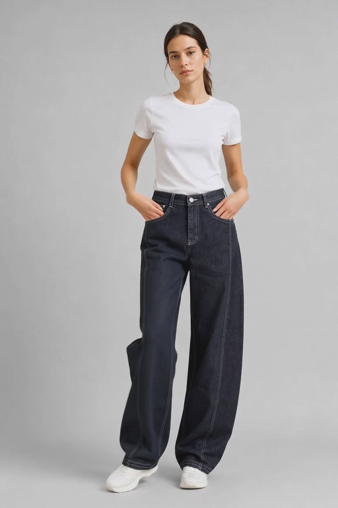 Model wearing Contrast-Stitch Curved-Leg Jeans in Black Gray, walking and turning to show the curved-leg fit and contrast stitching.