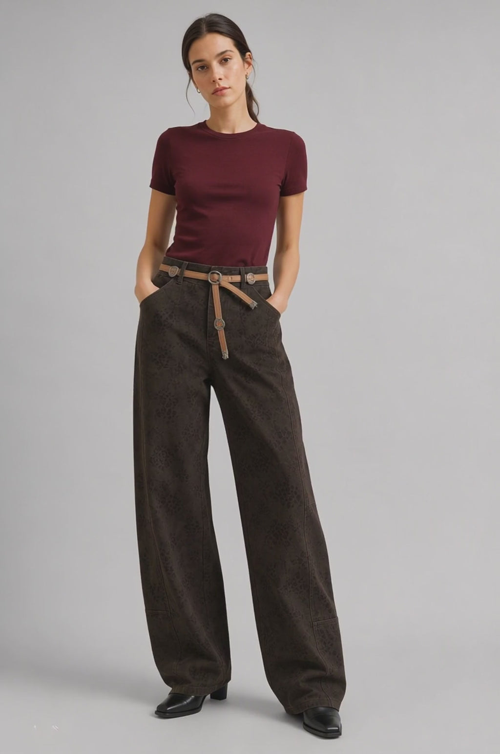 Model walks in, turns and poses in QAYQEY dark-brown leopard-jacquard curved-leg jeans with tan medallion belt, showing the front, side and back fit