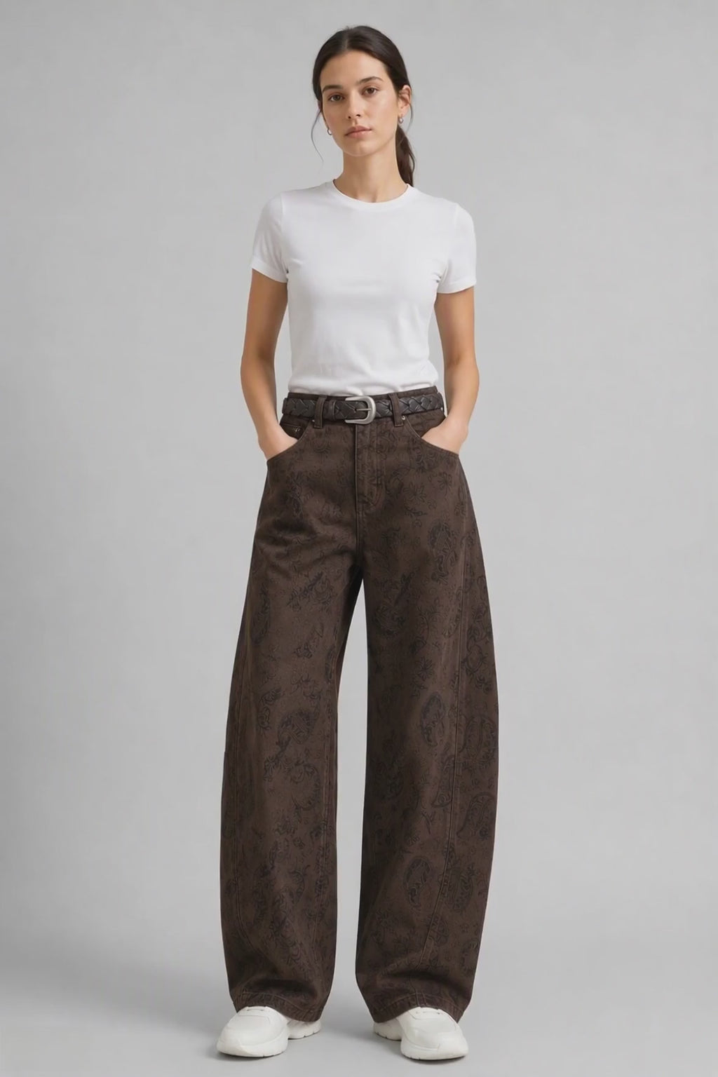 Model wearing Paisley-Jacquard Curved-Leg Jeans in Brown, walking and turning to show the curved-leg fit and all-over paisley jacquard pattern.