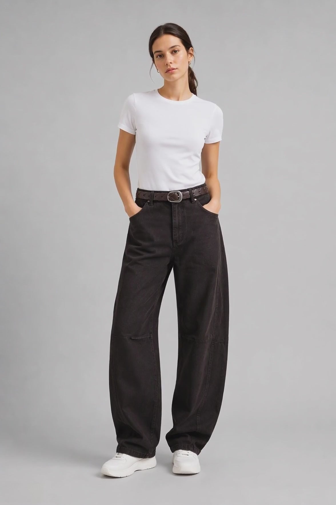Model wearing Curved-Leg Jeans in Dark Brown, walking and turning to show the curved-leg fit and dark brown denim finish.